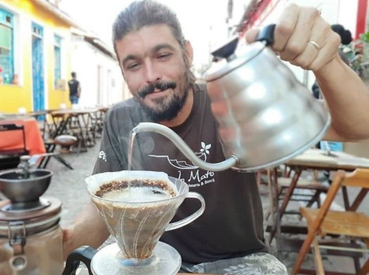 Barista coando café no Hario V60 em mesa na rua