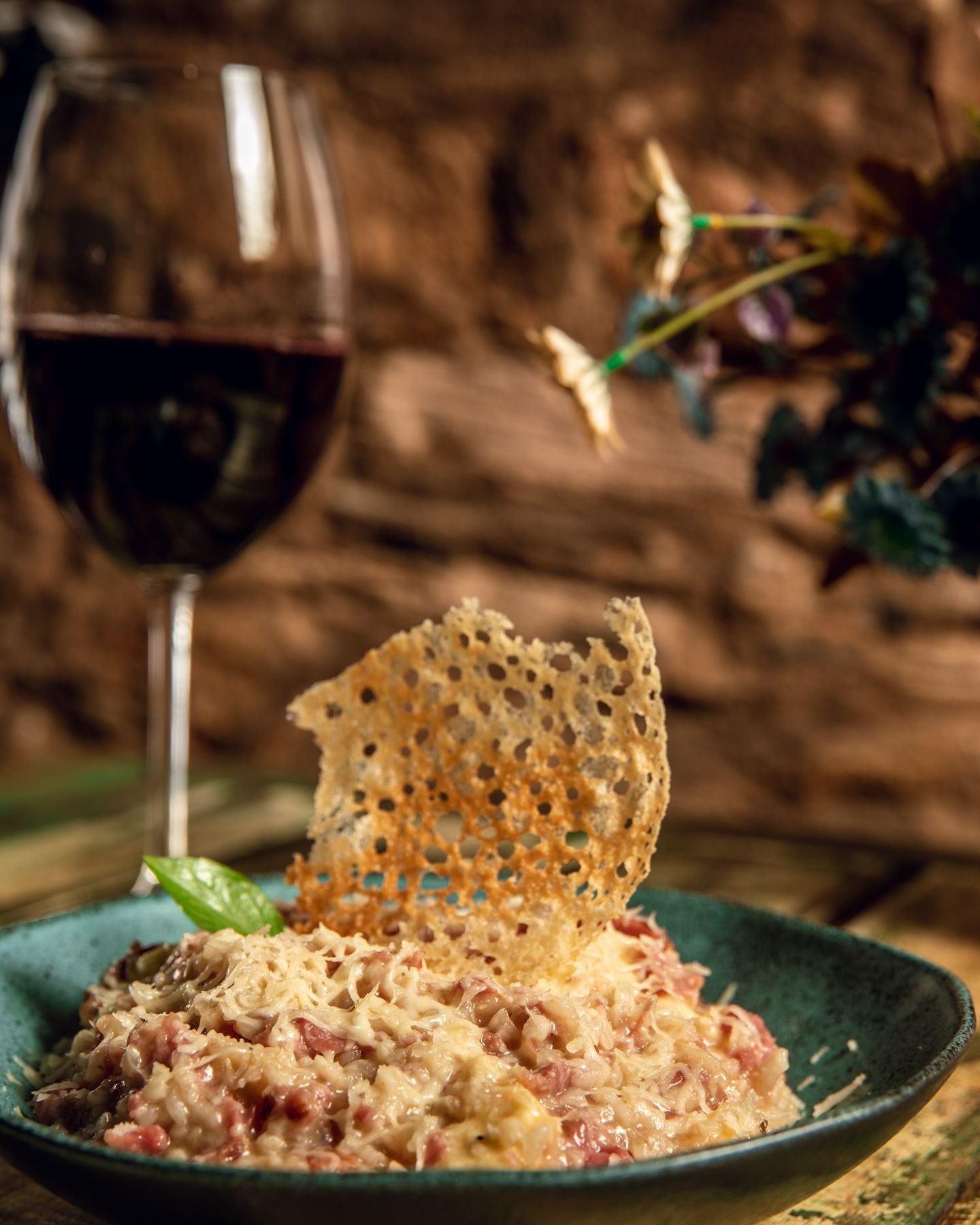 Prato com crocante de queijo e taça de vinho tinto no salão