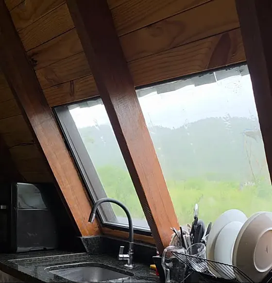 Janela inclinada da cozinha com a serra lá fora