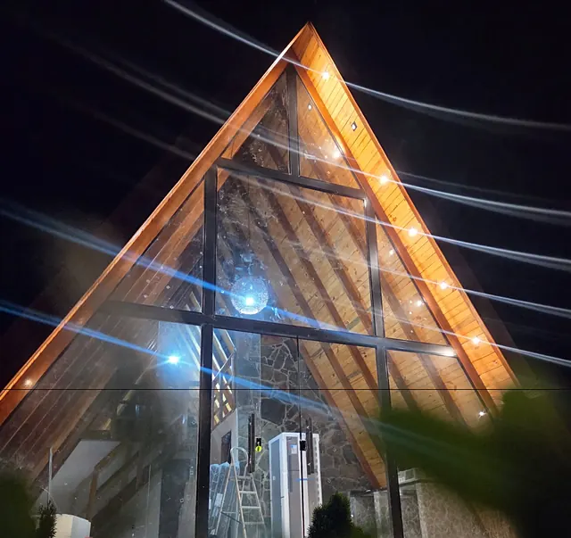 O A do chalé visto de baixo, à noite, com o cordão de luzes aceso