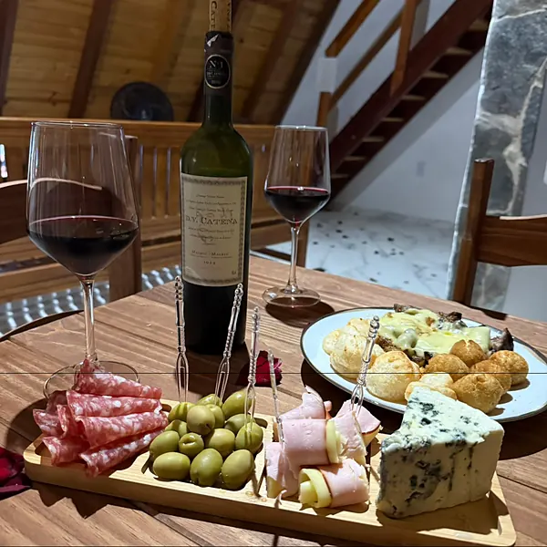 Vinho, taças e tábua de frios na mesa da sala