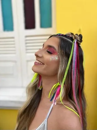 Clara com fitas coloridas no cabelo em clima de carnaval
